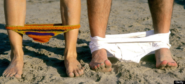 Man and woman drop their bathing suits at the beach.